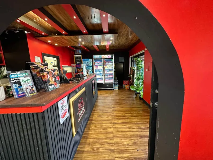 The Ibby’s counter — red walls, warm wood and the menu, with the kitchen behind