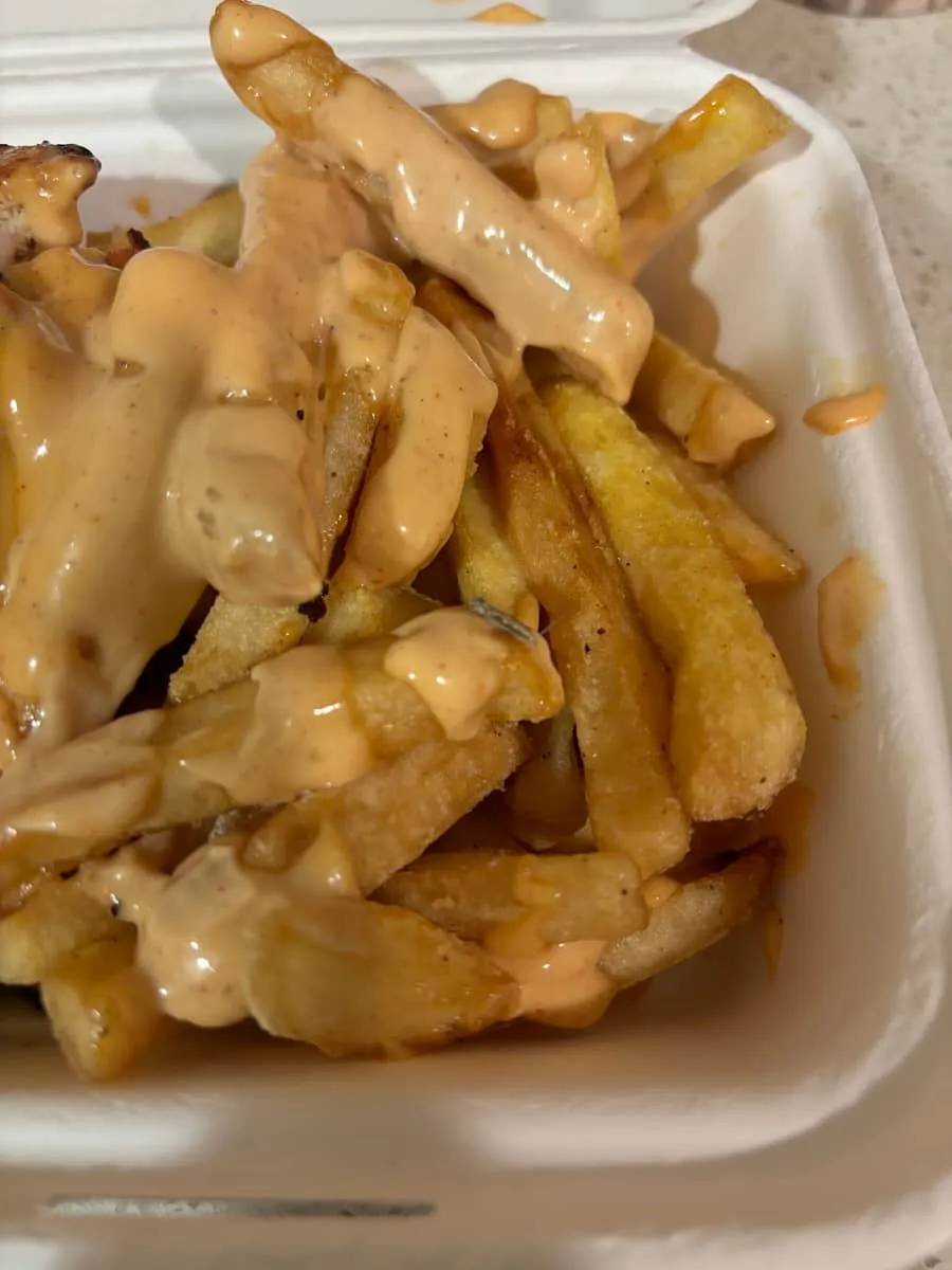 A box of golden fries loaded with creamy house sauce