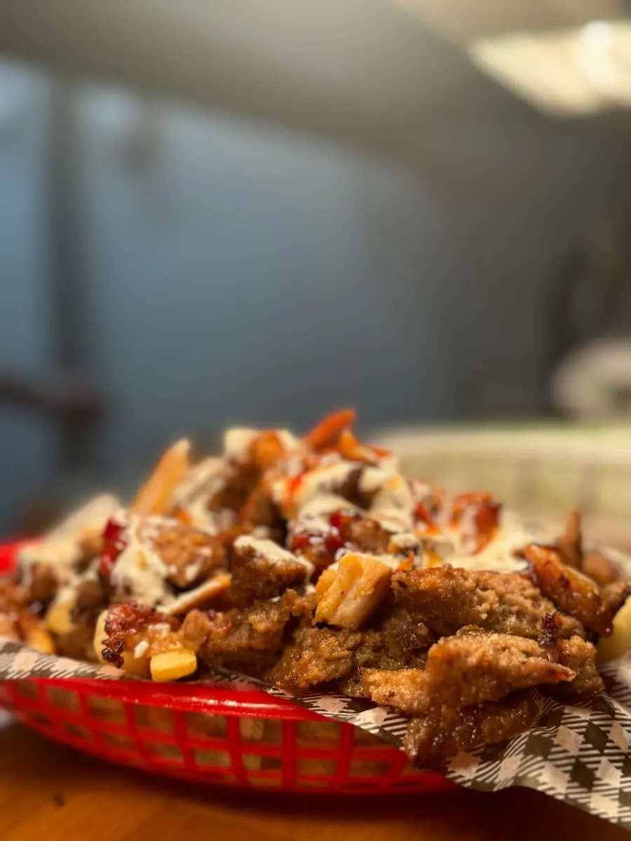 A meat-box snack pack — carved doner over chips with sauce in a red basket