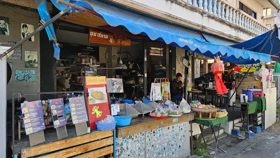 The blue-awning shophouse from the lane, with the Khao Soi menu board out front