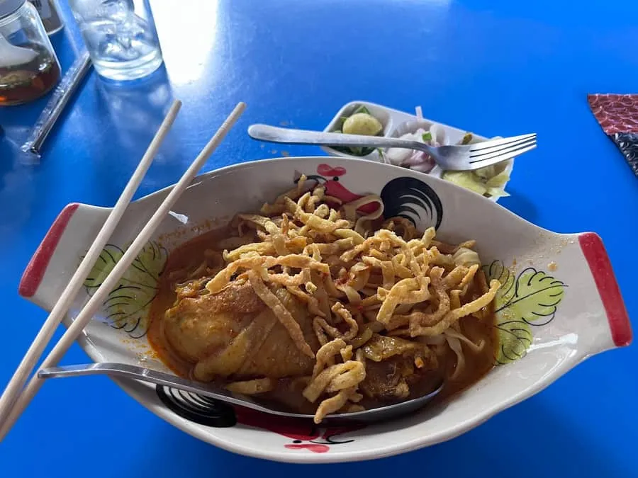 Chicken khao soi in golden coconut curry with crispy noodles and lime