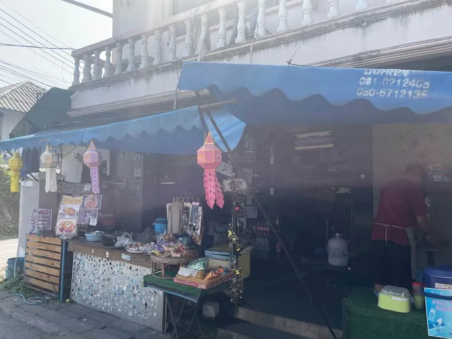 The shopfront in the morning light, lanterns hanging under the awning