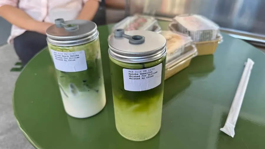 A matcha mamajito with mint and lime beside a salted maple matcha on a green table