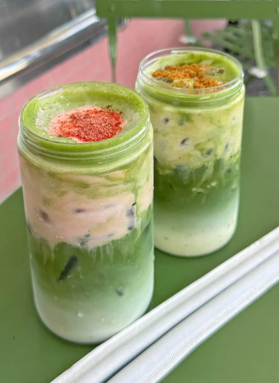A strawberry matcha — whisked matcha over pink strawberry milk, dusted with freeze-dried strawberry