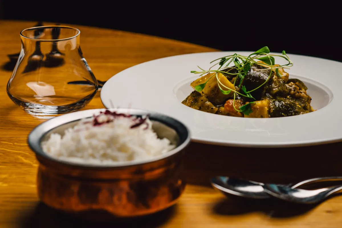 Aubergine curry with a copper bowl of basmati rice