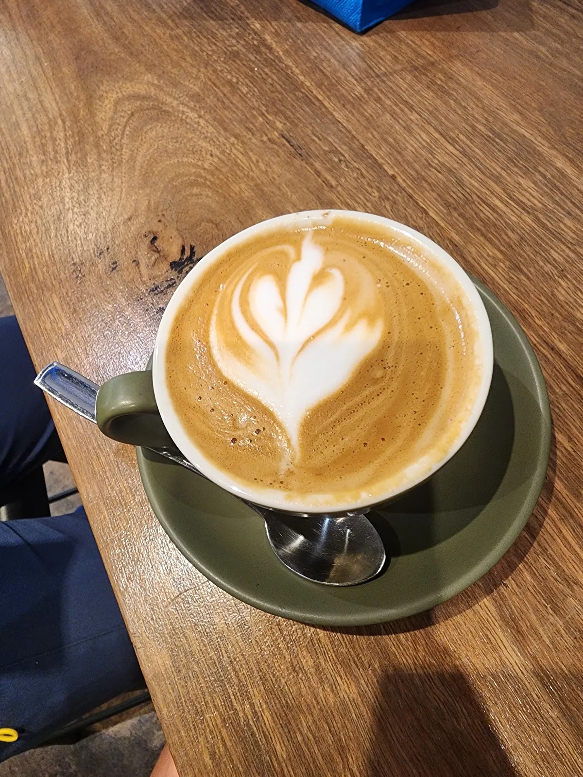 Flat white with latte art in an olive cup