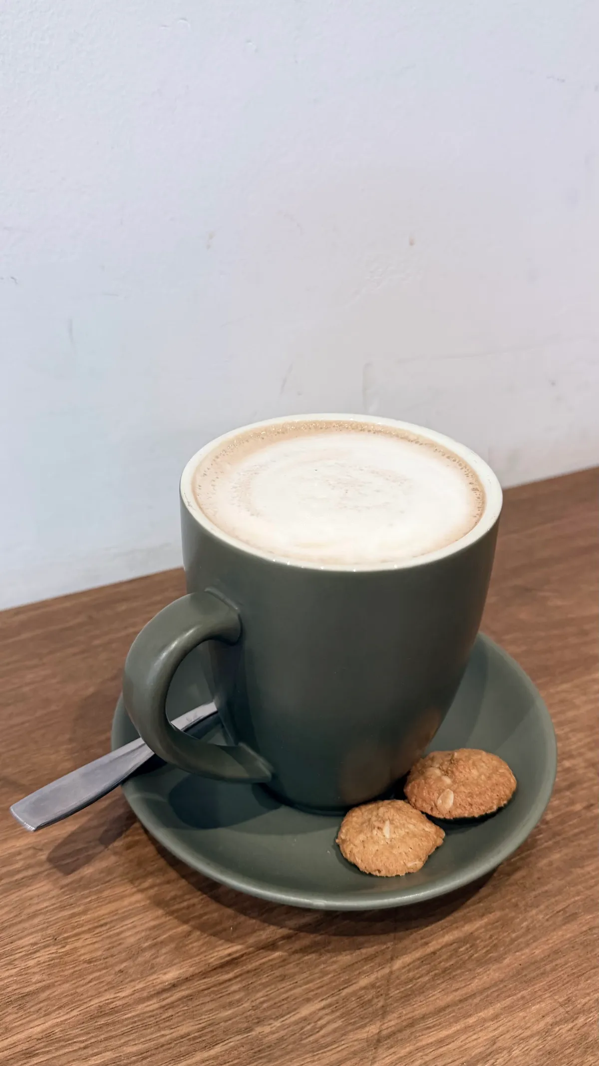 Latte in an olive mug with Anzac biscuits