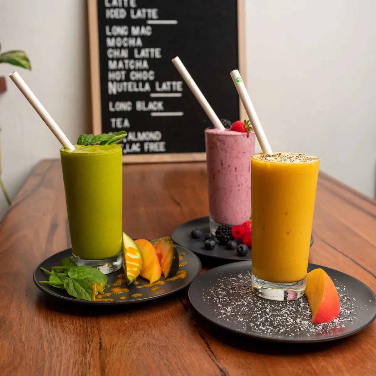 Green, berry and mango smoothies on black plates